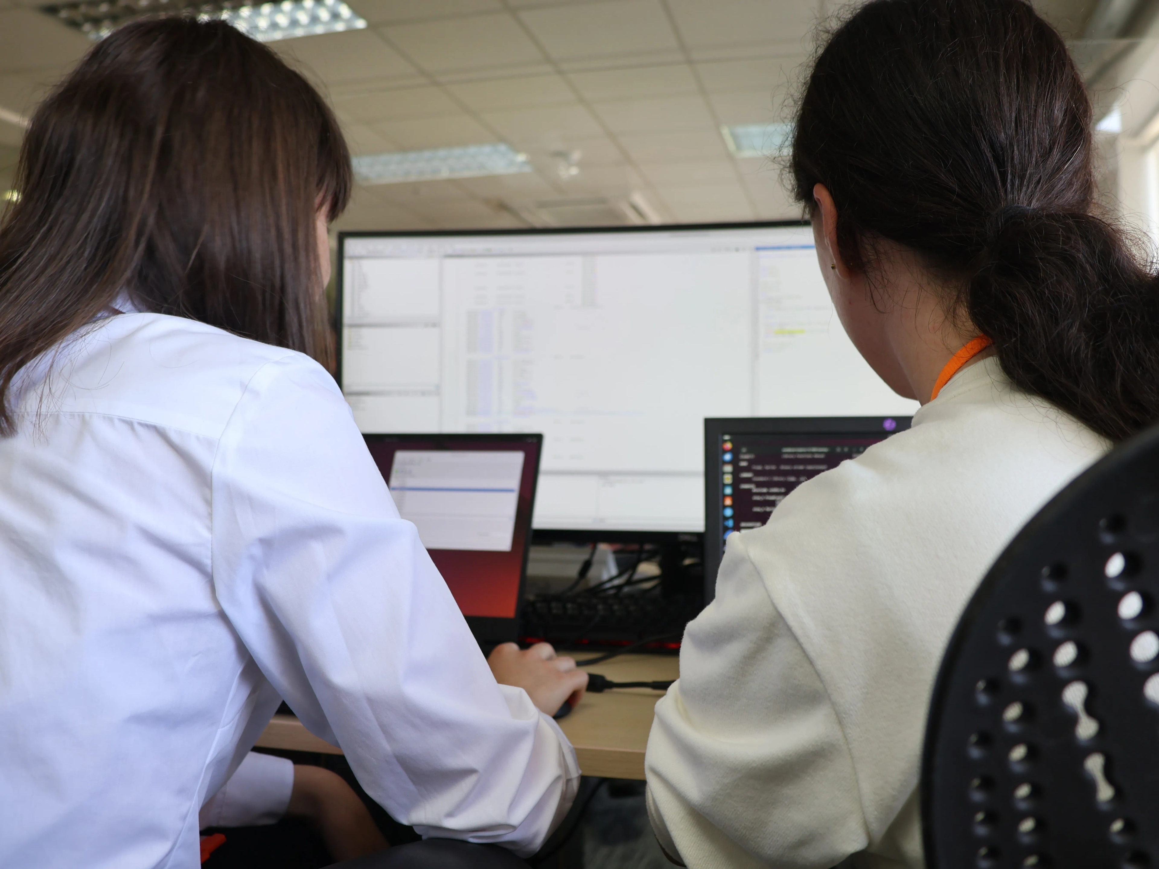 Two graduates sit at laptops working