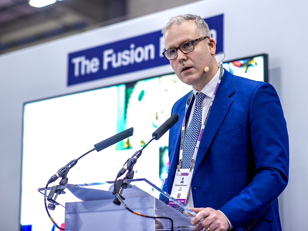 George Williamson, CEO of HMGCC stands at a lectern delivering a speech.